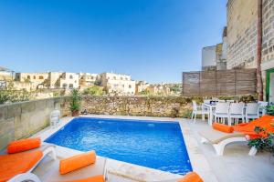a swimming pool with chairs and a table at The Valley Holiday Home in Kerċem