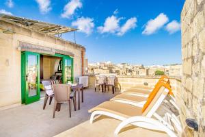 um pátio com cadeiras e mesas num edifício em The Valley Holiday Home em Kerċem