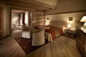 a bedroom with a large bed and two chairs at Castelir Suite Hotel in Panchia