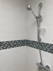 a shower in a bathroom with black and white tiles at Gresham in Kent
