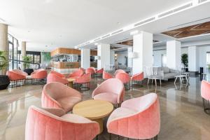a lobby with pink chairs and tables at Hotel Cimbel in Benidorm +65 photos