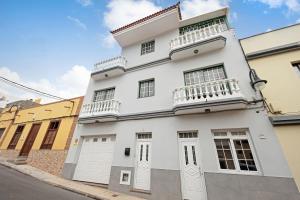 Casa blanca con puertas blancas y balcones en una calle en Ático Andrea, en Caleta de Interián