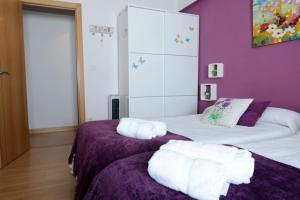 a bedroom with two beds with purple walls and white towels at DOMUS SALAMANCA EDISSON in Salamanca