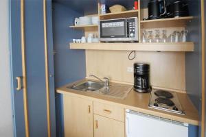eine kleine Küche mit einer Spüle und einer Mikrowelle in der Unterkunft Yachthafenresidenz - Wohnung 9203 / 894 in Kühlungsborn