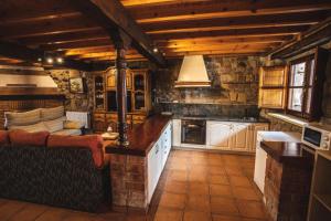 uma cozinha com tectos de madeira e uma parede de pedra em La Casa de Consuelo 3 em Viérnoles