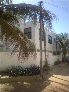 a white building with palm trees in front of it at Residence B&B Hibiscus in Dakar