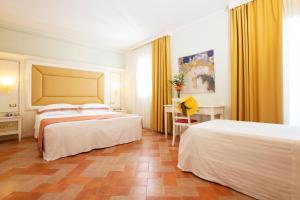 プリンチピナ・テッラにあるAntica Fornace Relais by La Principinaのベッド2台とデスクが備わるホテルルームです。