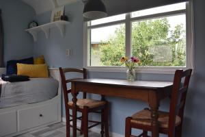 a room with a table and chairs and a window at Pipowagen ''Slapen by Co'' in Leerdam