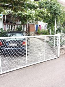 a chain link fence with a car parked behind it at APARTMANI NATALIJA in Bar