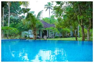 una piscina frente a una casa con árboles en Seclude Kerala, Marari Sands, en Mararikulam