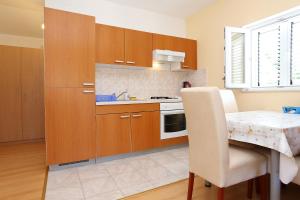 a kitchen with wooden cabinets and a table with a chair at Apartments with parking space Zuljana, Peljesac - 254 in Žuljana +18 photos