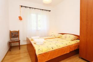 a bedroom with a bed with a chair and a window at Apartments with a parking space Zuljana, Peljesac - 252 in Žuljana