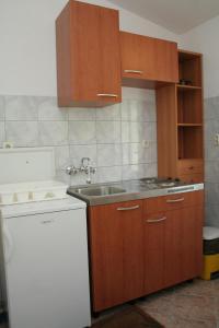 a kitchen with wooden cabinets and a sink at Seaside apartments with a swimming pool Viganj, Peljesac - 260 in Viganj