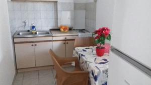 - une cuisine avec une table et un pot de fleurs dans l'établissement Secluded fisherman's cottage Krknata, Dugi otok - 399, à Žman