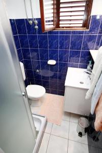 Baño de azulejos azules con aseo y lavamanos en Family friendly seaside apartments Zaton, Zadar - 298, en Zaton