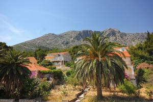 a group of houses and palm trees in front of a mountain at Apartments by the sea Orebic, Peljesac - 275 in Orebić