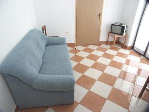 a living room with a blue couch and a television at Apartments with a parking space Punta kriza, Cres - 383 in Punta Križa