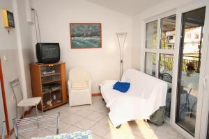Cette chambre dispose d'une chaise blanche et d'une télévision. dans l'établissement Apartments and rooms with parking space Njivice, Krk - 408, à Njivice