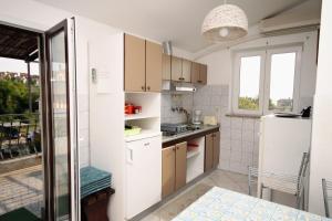 a small kitchen with a white refrigerator and a window at Apartments and rooms with parking space Njivice, Krk - 408 in Njivice