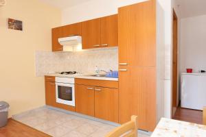 a kitchen with wooden cabinets and a sink and a refrigerator at Studio Zuljana 254a in Žuljana