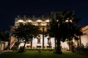 a building at night with trees in the foreground at Hanuwant Niwas Jodhpur in Jodhpur