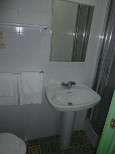 a white bathroom with a sink and a mirror at Pensión Fonda Vilalta in Ribes de Freser