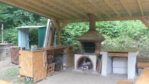 an outdoor oven under a roof in a yard at Chata Moštenica - Leginashytta in Moštenica