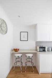 a kitchen with two bar stools and a counter at Gorgeous Modern Apartment near Redhill Station inc Private Garden & Parking in Redhill