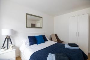 een slaapkamer met een blauw en wit bed en een spiegel bij Gorgeous Modern Apartment near Redhill Station inc Private Garden & Parking in Redhill