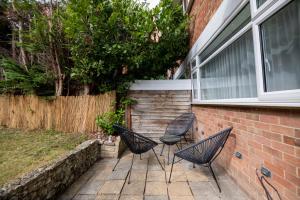 un patio avec trois chaises et un bâtiment dans l'établissement Gorgeous Modern Apartment near Redhill Station inc Private Garden & Parking, à Redhill