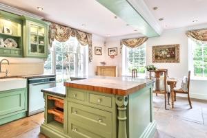 a large kitchen with green cabinets and a table at Walcot Hall - Stunning Stately Home set in 27 acres of parkland and sleeping 16+ in Alkborough