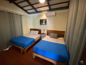 two beds in a room with blue sheets at Lote 44 Guesthouse in El Zonte