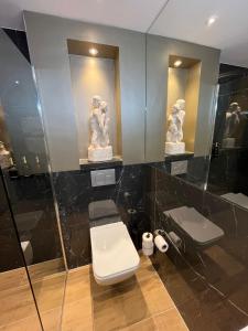 a bathroom with a toilet and two statues on the wall at Het Waterhof in Leiden +14 photos