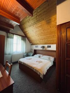 a bedroom with a large bed and a wooden ceiling at Útulna Craft - penzion Veronika in Pec pod Sněžkou