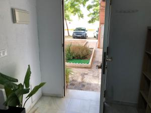 eine offene Tür zu einer Einfahrt mit geparktem Auto in der Unterkunft Tablada Los Remedios in Sevilla