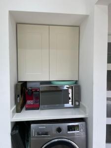 een keuken met een magnetron en een wasmachine bij Rooms in a beautiful house with free on St parking in Hove