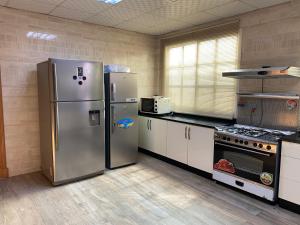 a kitchen with two stainless steel refrigerators and a stove at Private Cottage in Sharjah