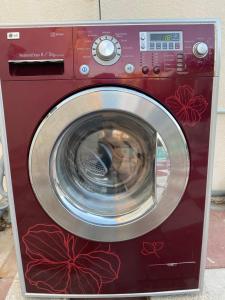 a red washing machine with red flowers painted on it at Private Cottage in Sharjah