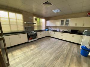 a large kitchen with white cabinets and a wooden floor at Private Cottage in Sharjah