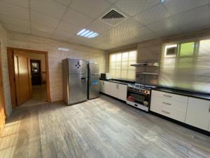 a large kitchen with stainless steel appliances and wooden floors at Private Cottage in Sharjah