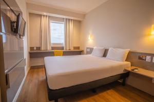 a hotel room with a bed and a tv at Transamerica Fit Campo Grande in Campo Grande