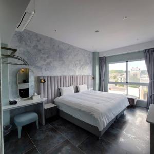 a bedroom with a bed and a desk and a television at 芙蘿拉萃旅 in Taitung City