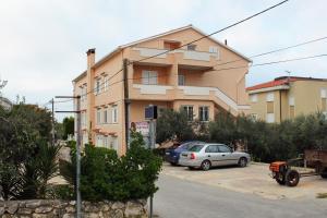 a building with two cars parked in a parking lot at Apartments with parking space Novalja, Pag - 9419 in Novalja