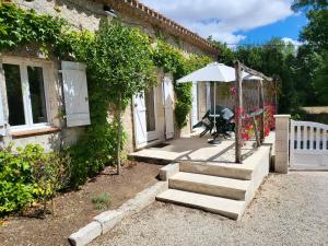 a house with a porch with stairs and an umbrella at La petite Maison in Ronsenac