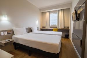 a hotel room with a large bed and a television at Carandá Hplus Express in Campo Grande