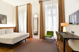 1 dormitorio con cama, escritorio y silla verde en Hotel Zenit Budapest Palace, en Budapest