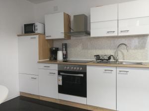 een keuken met witte kasten en een zwarte oven bij Apartment Smoljanac 12345c in Smoljanac