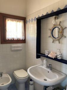 een badkamer met een wastafel, een toilet en een spiegel bij Apartmán Panoramico in Costa Paradiso