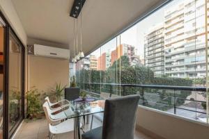 balcón con mesa y sillas y ventana grande en Departamento semipiso, 2 habitaciones, con parrilla y estacionamiento privado en Buenos Aires