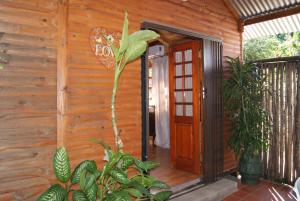 uma casa de madeira com uma porta e algumas plantas em Fern Cottage em Louis Trichardt